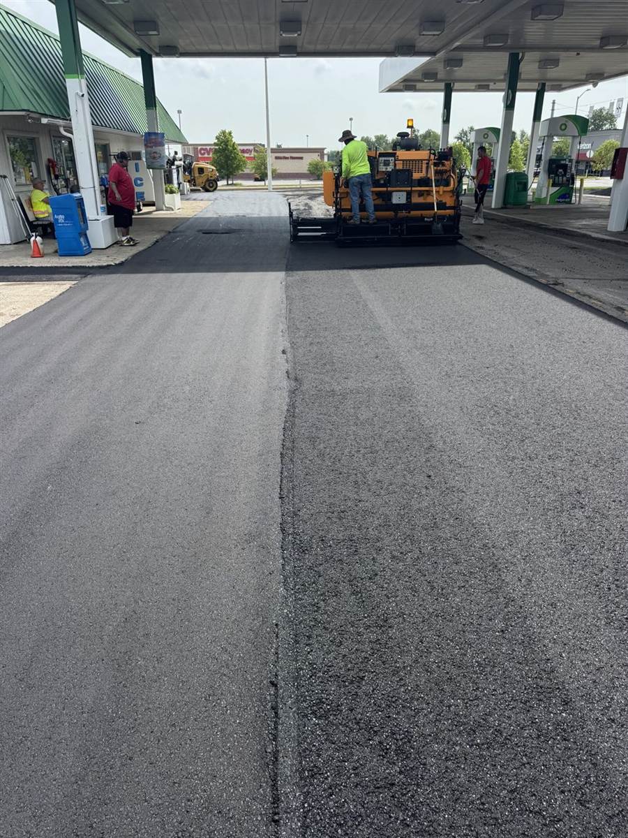 Paver at a busy gas station during a commercial paving job