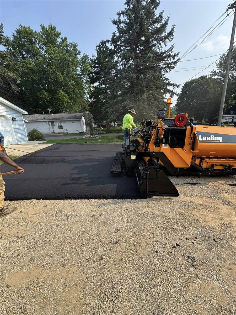 Hot asphalt mix being laid by a paver